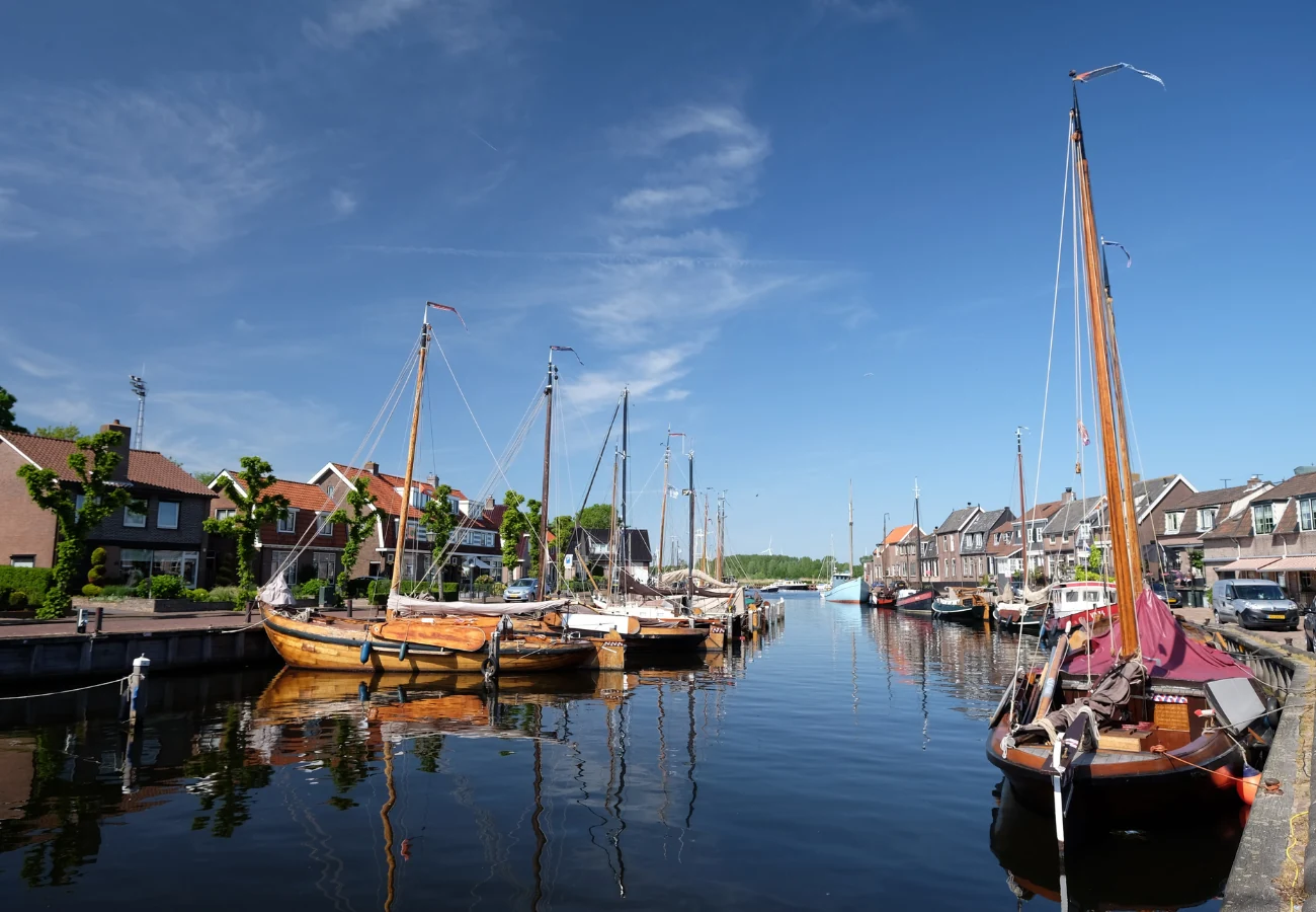 Historische botters in de haven van Bunschoten-Spakenburg met karakteristieke visserswoningen langs het water bij glas van jan